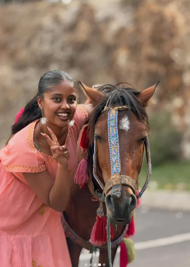 Efratah smiling beside a decorated horse near Entoto